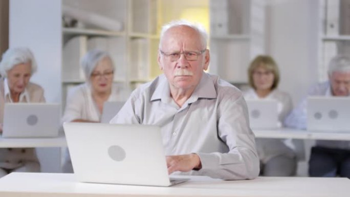 严肃的老人在计算机课上摆姿势