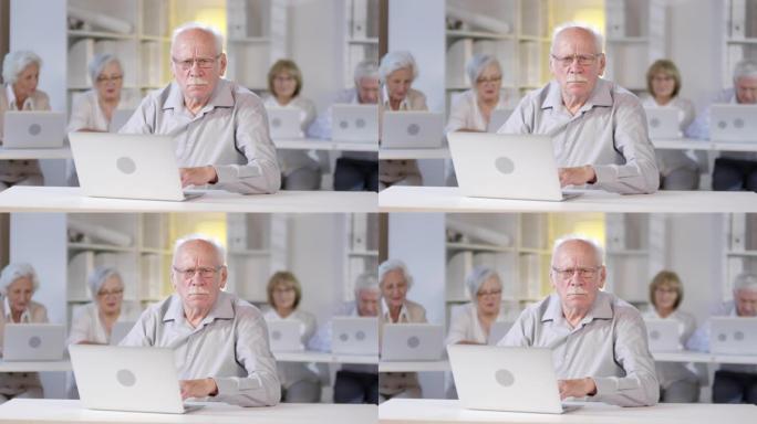 严肃的老人在计算机课上摆姿势