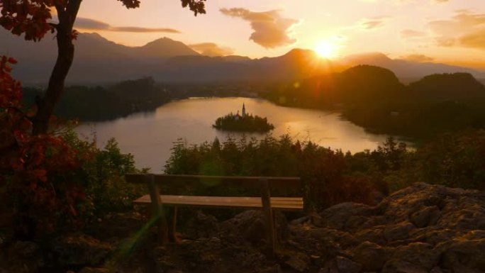 特写: 令人叹为观止的日落照亮空长凳，俯瞰湖泊
