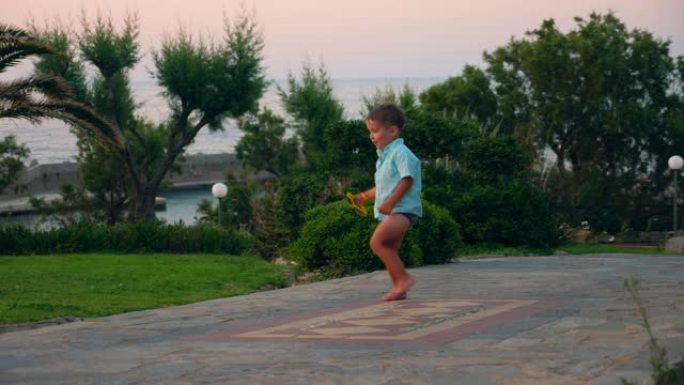 小男孩在海上度假胜地的道路上奔跑和行走