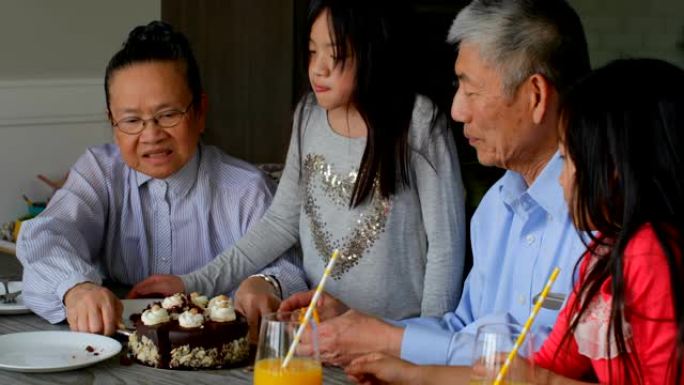 亚洲老祖母在舒适的4k家里供应生日蛋糕的前视图