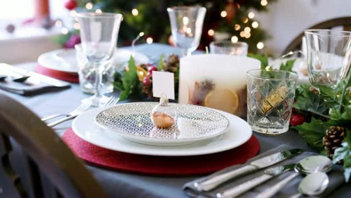 一个节日圣诞餐桌，盘子上摆着摆设的名片夹，绿色和红色季节性装饰，细节