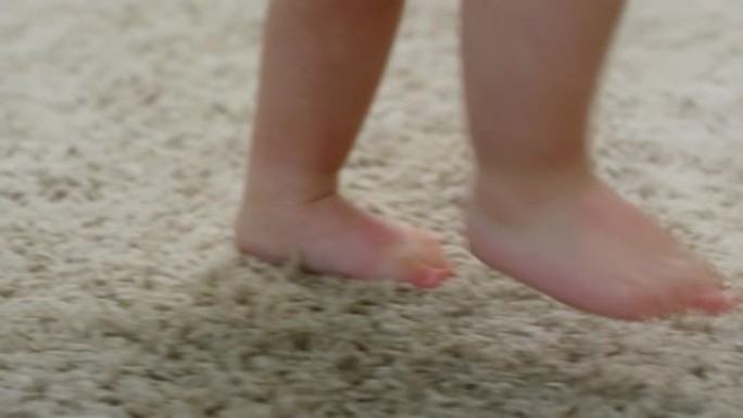 赤脚蹒跚学步的孩子在家独自行走