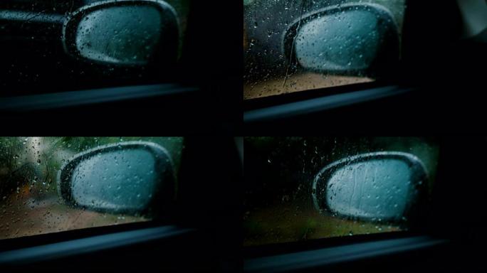 电影特写镜头，从行驶中的汽车内部可以看到散焦的侧视镜，重点放在窗户上的雨滴上。