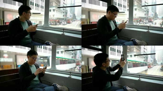 亚洲男子在香港城市电车上使用电话。