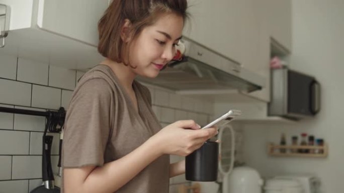 年轻女子坐在舒适的厨房里，用手机工作。
