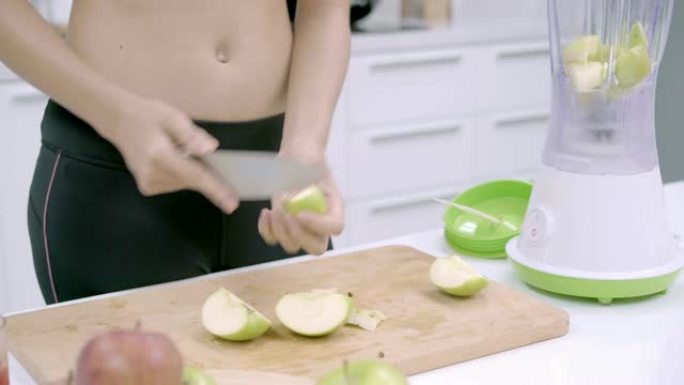 运动型亚洲女性在厨房准备制作苹果汁的配料，穿着运动服的女性在家中使用有机水果大量营养制作苹果汁。健康