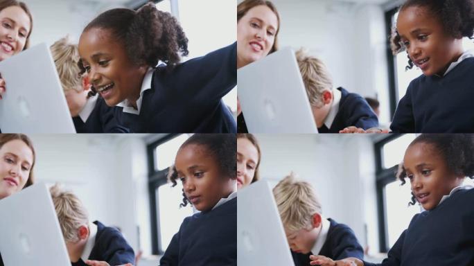 小学生在小学课堂上与一名男孩和女老师一起使用笔记本电脑，特写