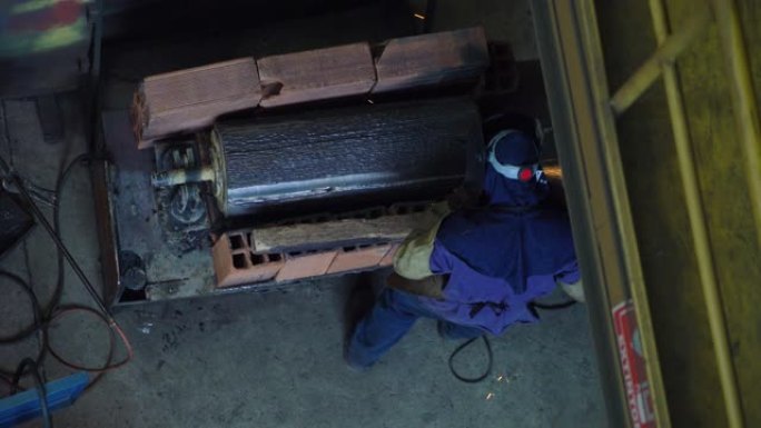 无法识别的蓝领工人在冶金工厂用机器抛光一块钢
