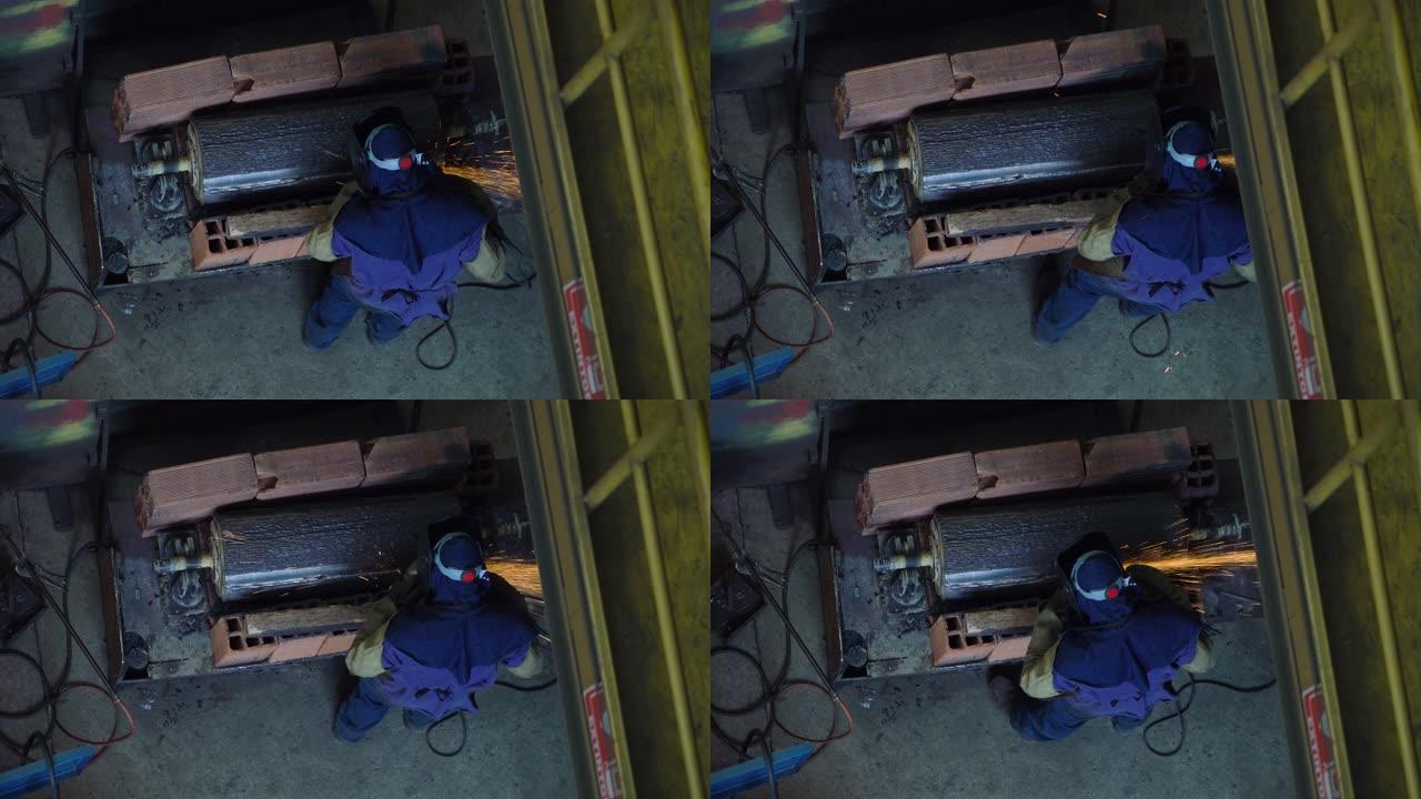 无法识别的蓝领工人在冶金工厂用机器抛光一块钢
