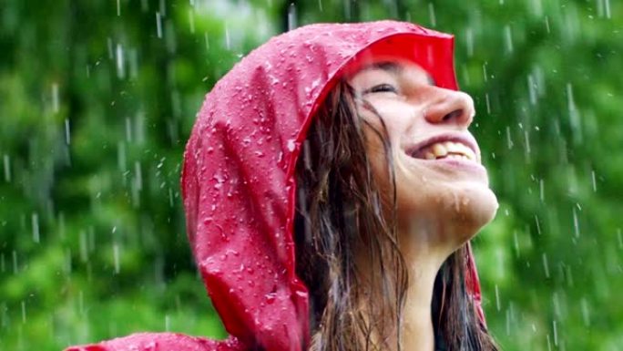 一个快乐的女人在雨中微笑，女人沉浸在快乐自由的雨中慢动作下的舞蹈中。