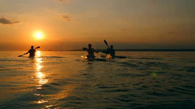 一群赛艇运动员正划独木舟进入夕阳