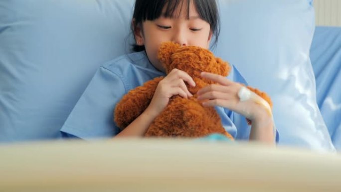 喜怒无常的女婴坐在医院的床上，独自看着泰迪熊。中国和香港的医疗系统压力时刻