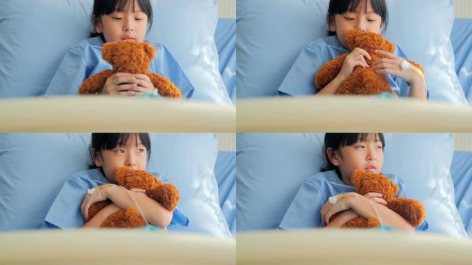 喜怒无常的女婴坐在医院的床上，独自看着泰迪熊。中国和香港的医疗系统压力时刻
