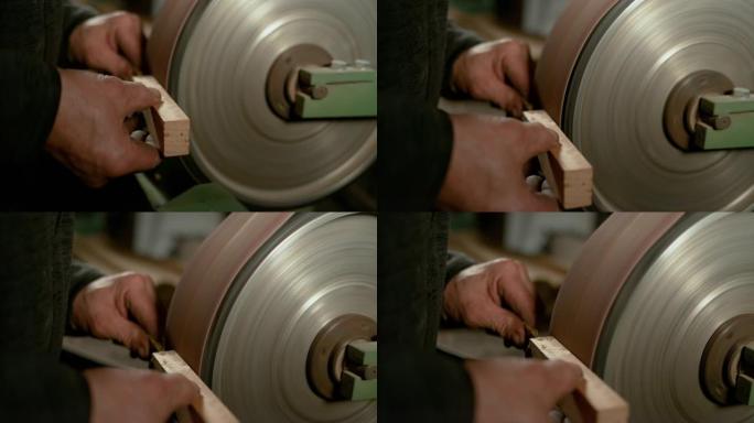 特写: 木匠将一块木头靠在用砂纸覆盖的轮子上