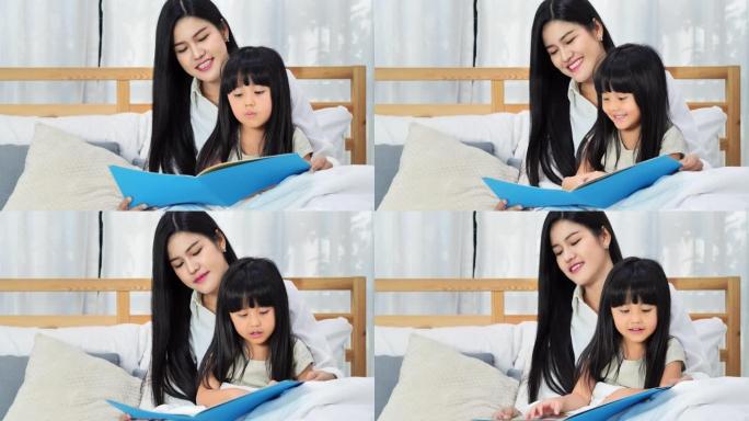 一个年轻的母亲和她的小女孩正在卧室里看书。女人带着孩子看书。家庭观念。教育。快乐的亚洲家庭。在一起度