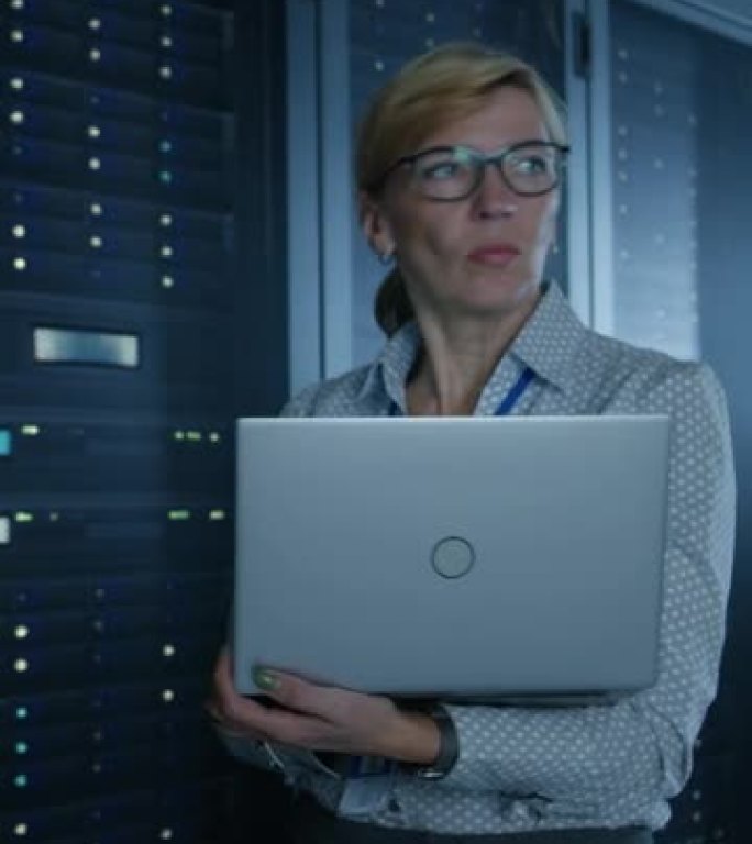 在数据中心: 女it技术人员在笔记本电脑上运行维护程序，控制操作服务器机架的最佳功能。现代超级计算机