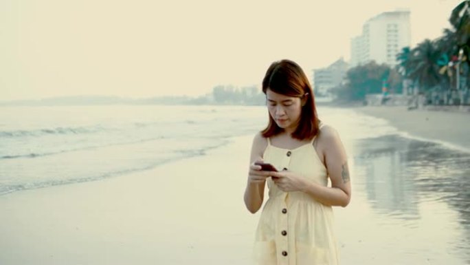 日落时分，亚洲女性在海上通过智能手机打字