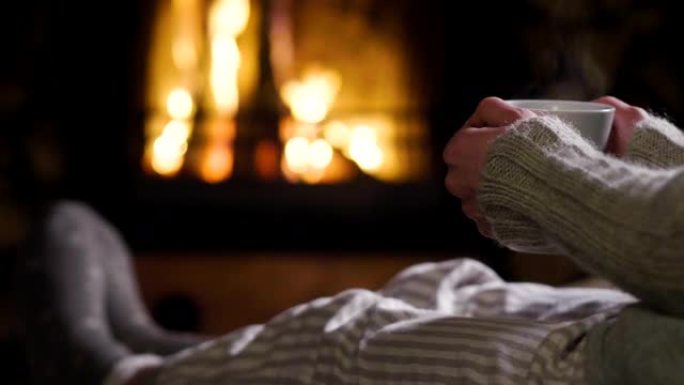 寒冷的秋天或冬天的晚上。人们用毯子和茶在炉火旁休息。
