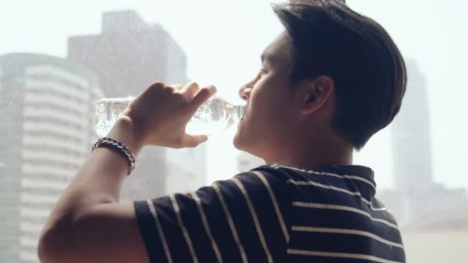 年轻的亚洲男子用玻璃喝水。