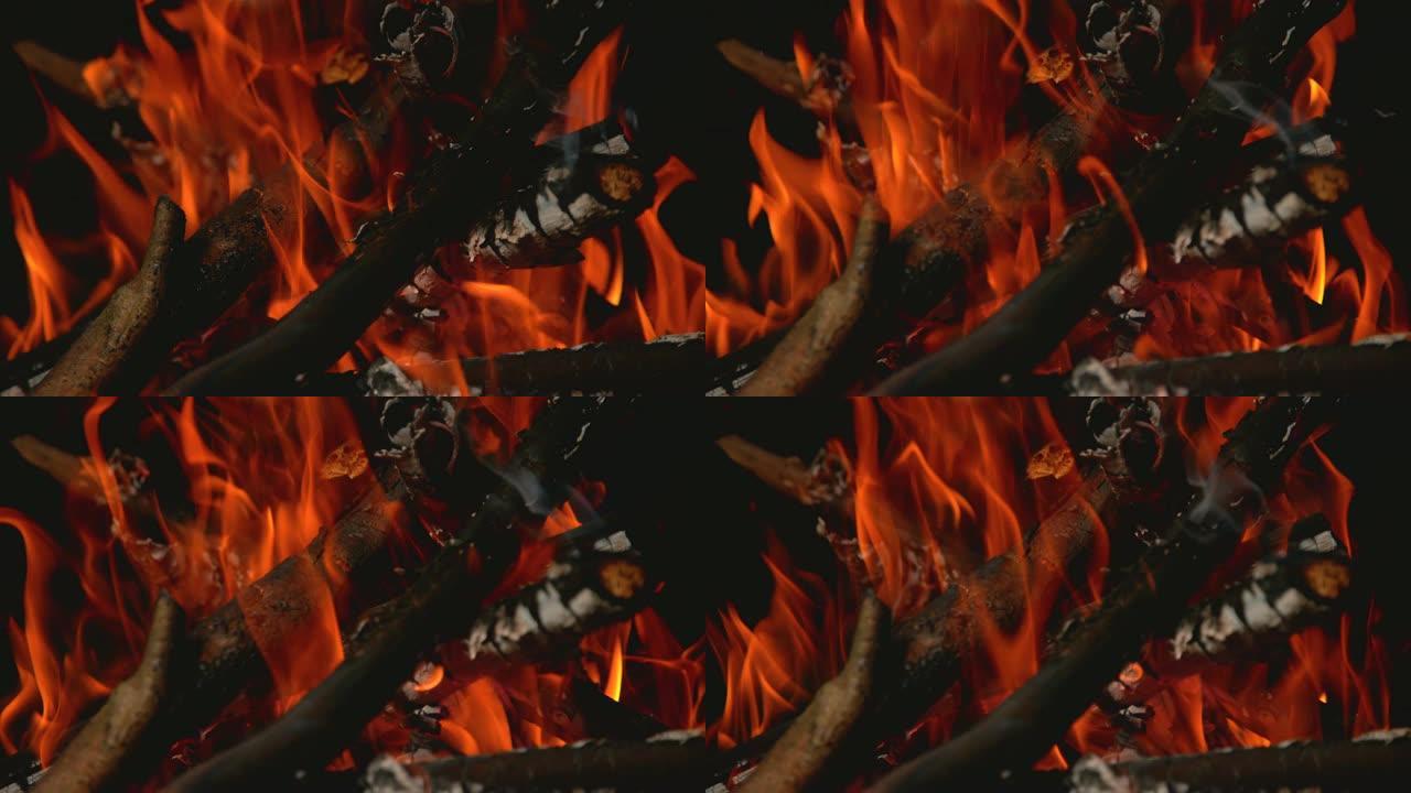 时间重新绘制: 橙色火焰吞没篝火中的树枝的电影镜头。