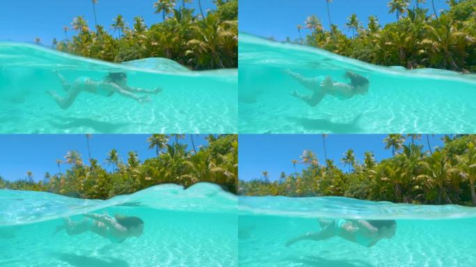 慢动作: 女性游客在原始海水中的沙滩上潜水
