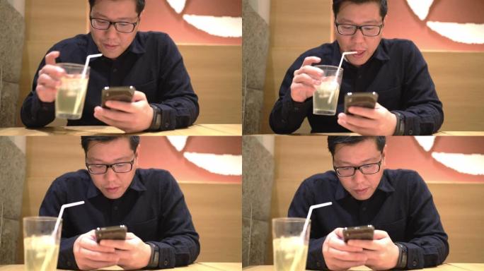 亚洲男子在餐厅玩手机等待食物