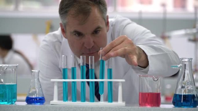 实验室的男科学家用蓝色液体抓住试管