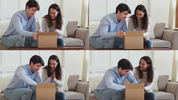 兴奋的年轻夫妇顾客打开纸板箱坐在沙发上