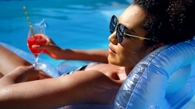 年轻混血女子在游泳池4k浮动泳池躺椅上放松的特写