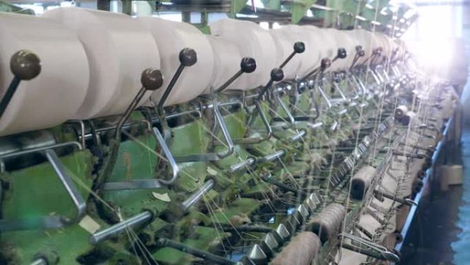 金属机器在纺织厂与线一起工作，将它们盘绕到线轴上。