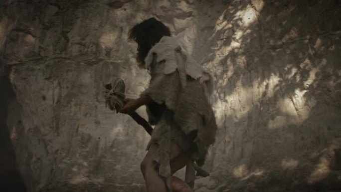 戴着动物皮的原始穴居人拿着尖石锤从洞穴中出来，环顾四周，探索史前森林，准备猎杀动物猎物。尼安德特人进