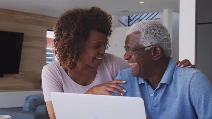 老年非裔美国夫妇在家中使用笔记本电脑的肖像