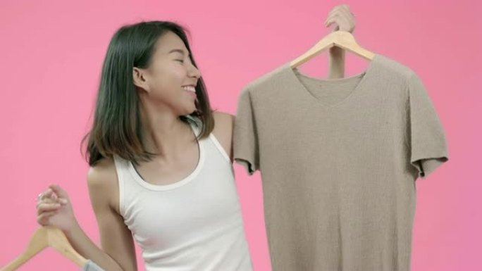 年轻漂亮时尚的亚洲女性选择粉色背景下的休闲服装工作室拍摄。快乐微笑可爱的快乐女人快乐成功。