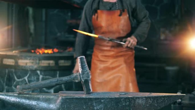 男子用锤子击刀，在铁匠铺上工作。铁匠锻造熔融金属