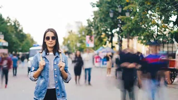 孤独女孩游客的延时站在现代城市，人们四处走动，看着相机。青年生活方式、社会和孤独观念。