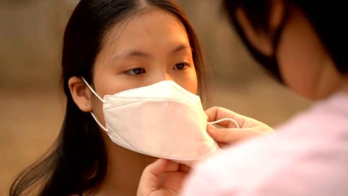 手持慢动作拍摄妈妈护理女儿脸上戴着空气污染面具