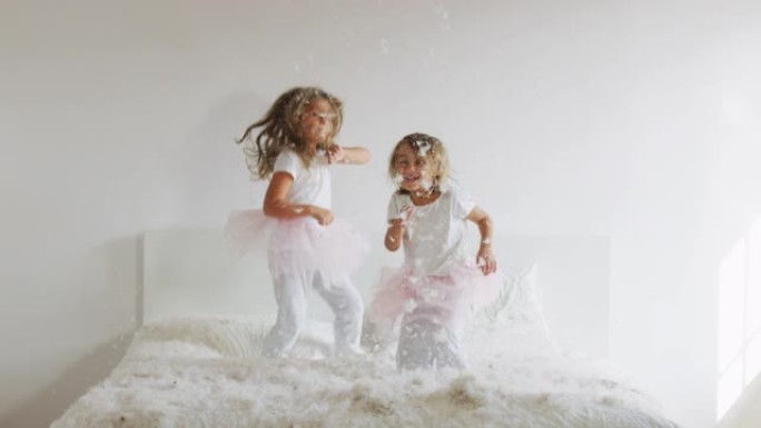 两个姐妹，穿着白色睡衣，用枕头打架，玩得很开心。