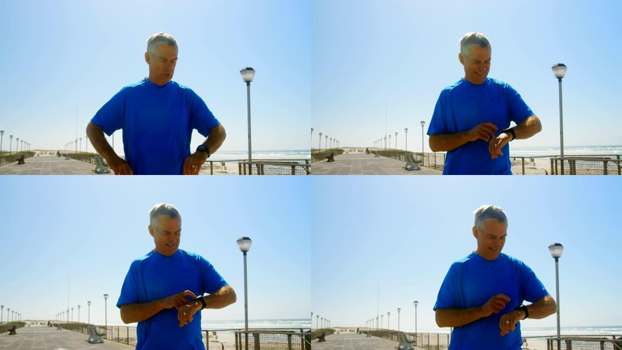 在4k海滩的长廊上使用智能手表的活跃高级高加索人的前视图