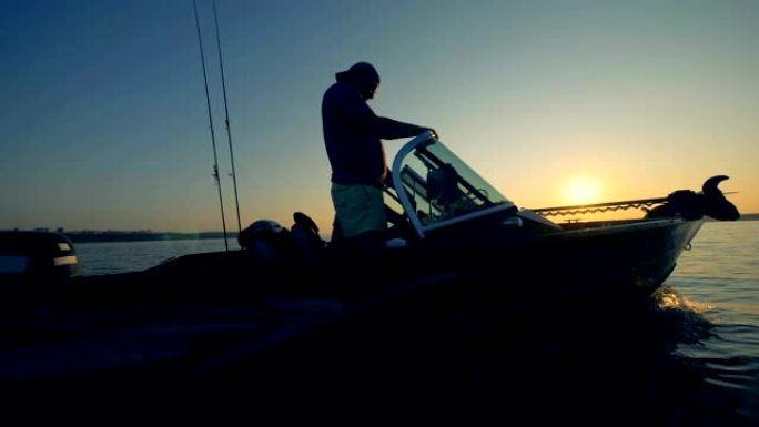 两名垂钓者在日出时驾驶汽艇钓鱼