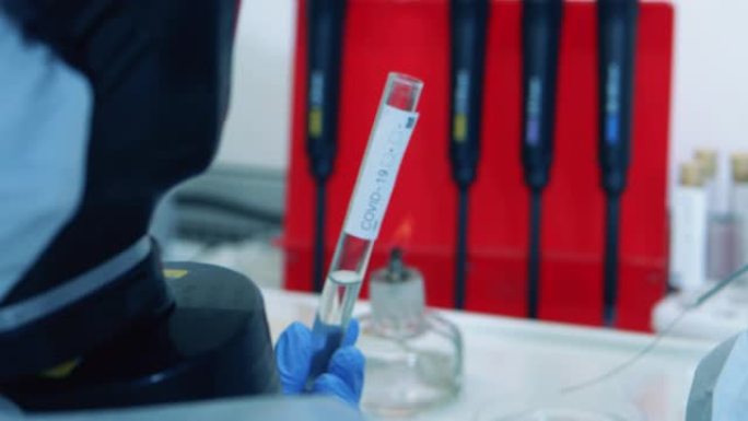 科学家在与冠状病毒一起工作时用液体填充玻璃管。