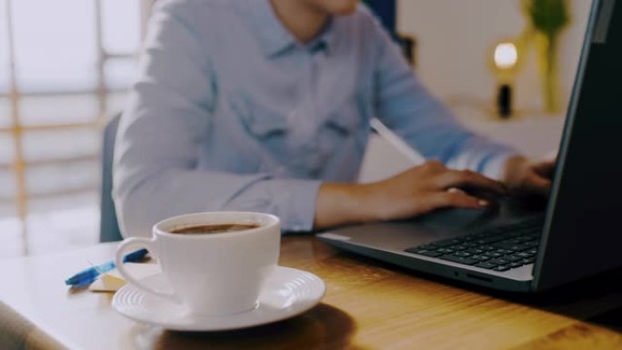DS女人在家里用笔记本电脑工作时喝杯咖啡