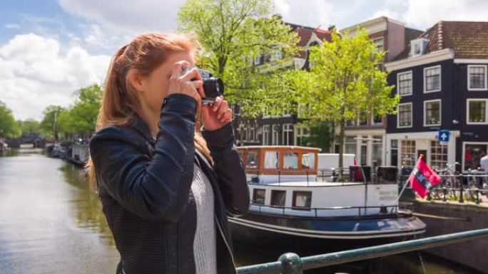 女人在阿姆斯特丹旅行，用老式模拟相机为运河拍照