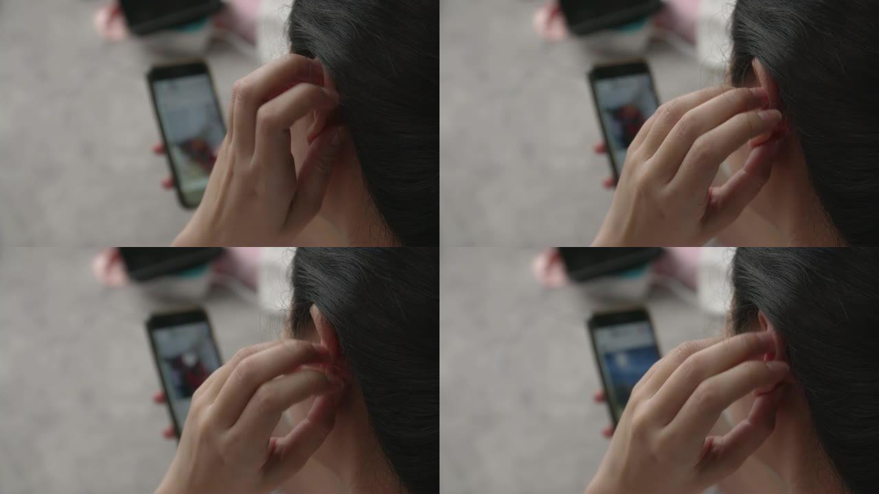 亚洲女性使用智能手机，耳朵发痒