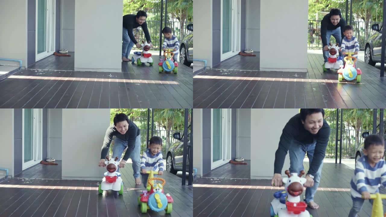 亚洲单身爸爸带着儿子在现代房子前草坪上玩玩具车的4k慢动作镜头，用于自学或家庭学校，家庭和童年的概念