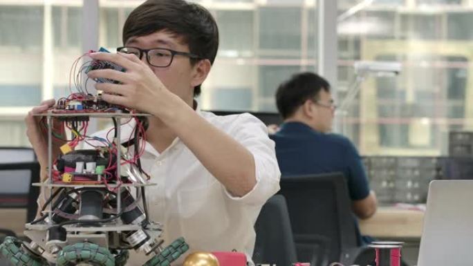 年轻的亚洲电子开发工程师与机器人一起工作，在车间的机器人原型电路中测量信号。有技术或创新概念的人。