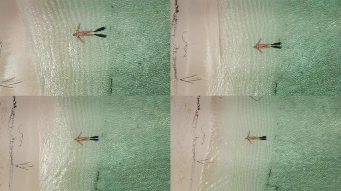 在拥有白色沙滩和清澈海水海湾的荒岛风景中，与帕雷奥一起在风中行走的女人的鸟瞰图