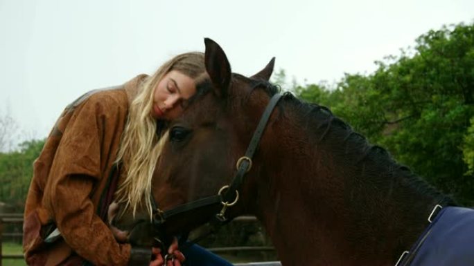 女人在4k牧场的木栅栏上拥抱马