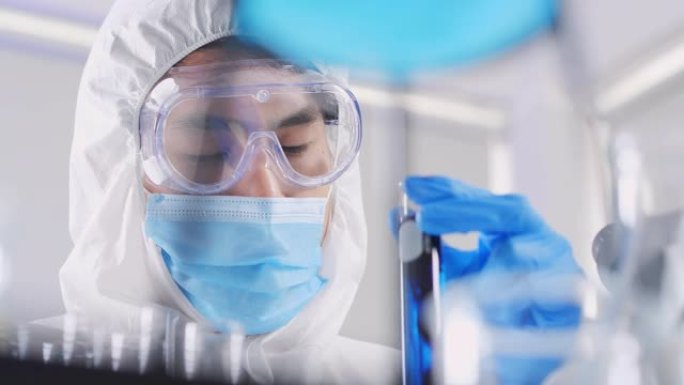 亚洲科学家对混合试管进行实验室测试的信心的特写，实验室中含有化学液体的实验对冠状病毒病毒或Covid