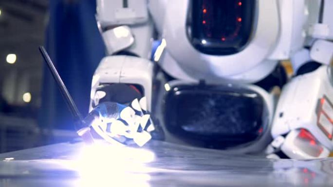 白色机器人焊接在金属板上，特写。